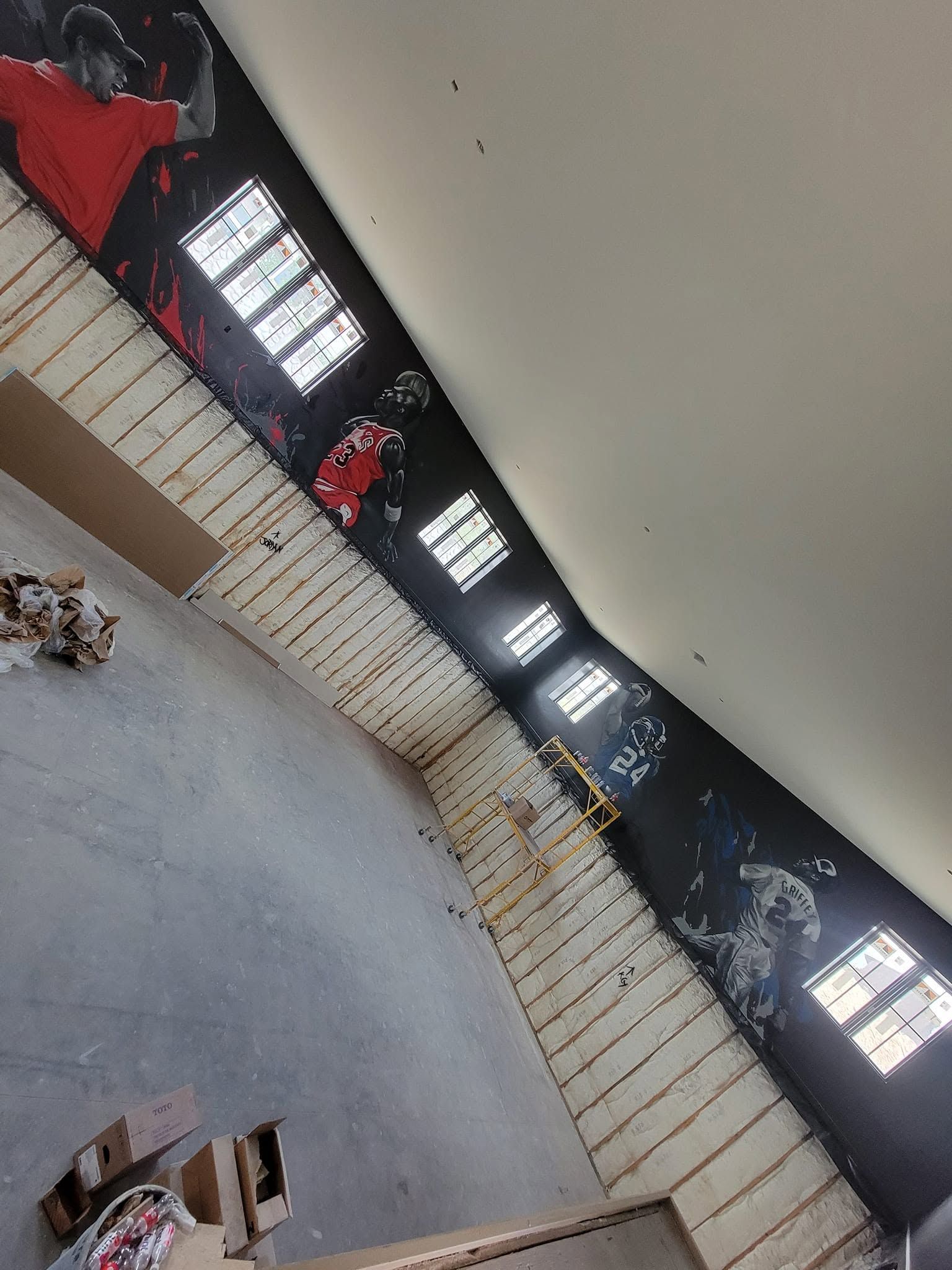 The full length of the court wall, dark paint running from the hardwood up to the ceiling between tall windows