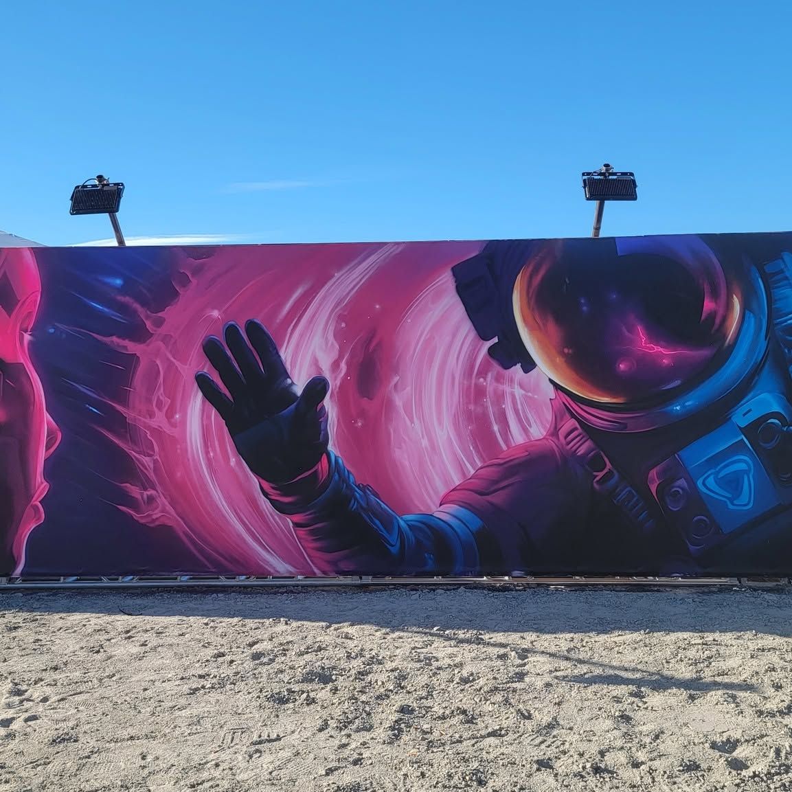 The finished festival wall end to end: a pink vortex, a reaching glove and an astronaut in a mirrored visor