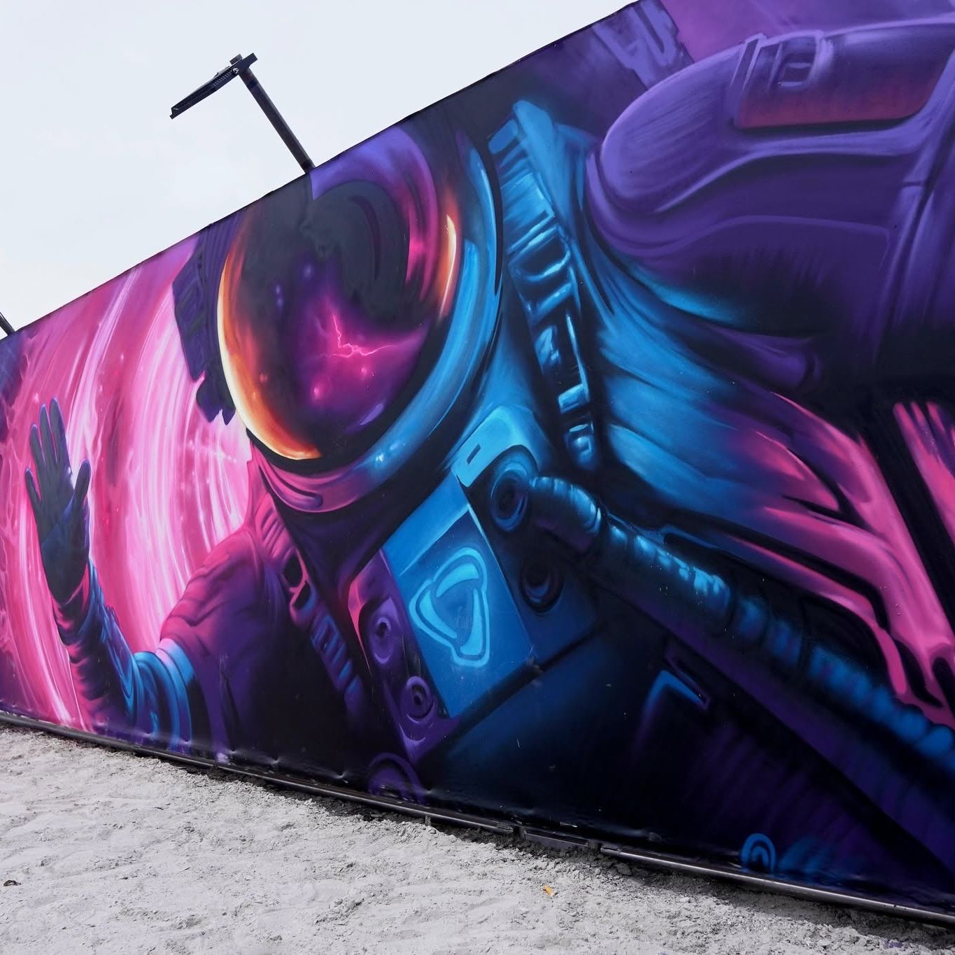 Long festival wall painted with an astronaut in pink, purple and blue, the Das Energi banner beside it