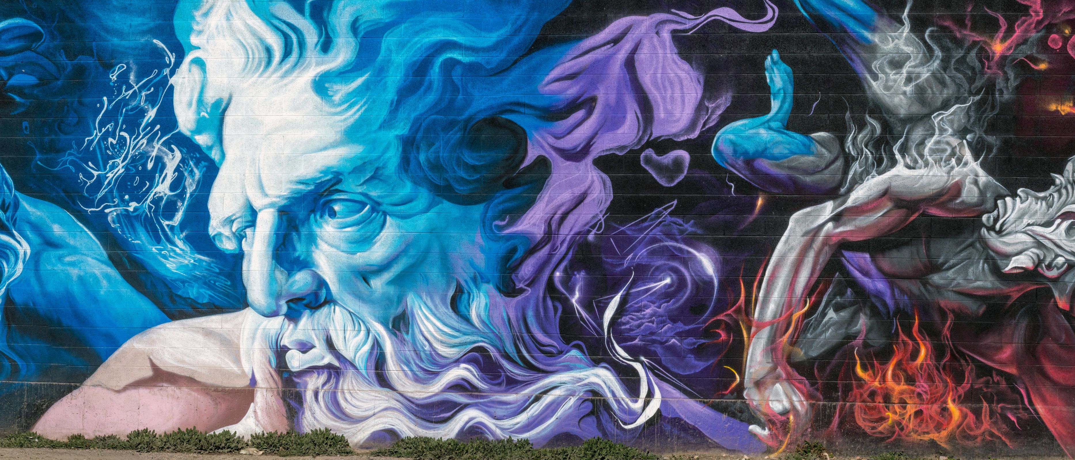 A long cinder-block wall painted end to end with Greek gods in blue, purple and fire