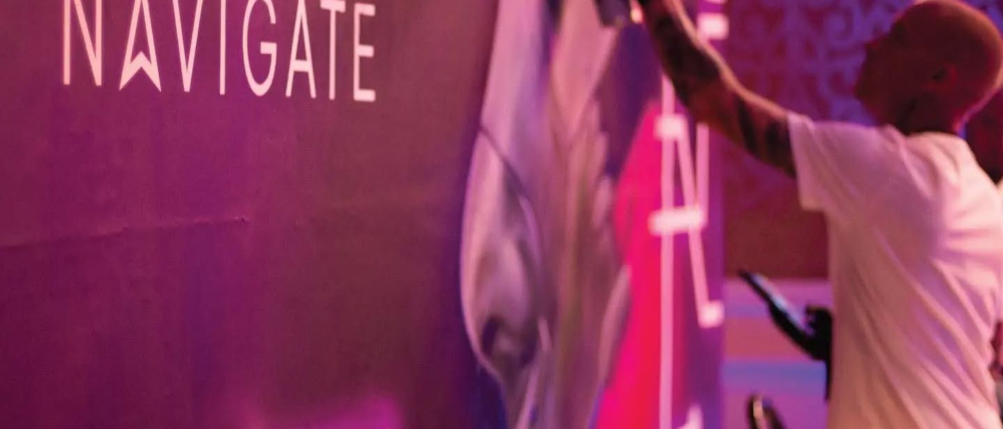 Spray-painting live on a magenta backdrop branded for Pluralsight's Navigate event