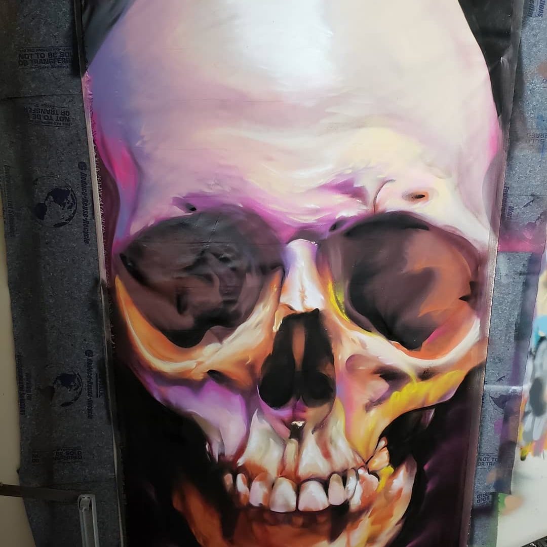 Human skull study painted freehand in aerosol with warm pink and orange tones on canvas