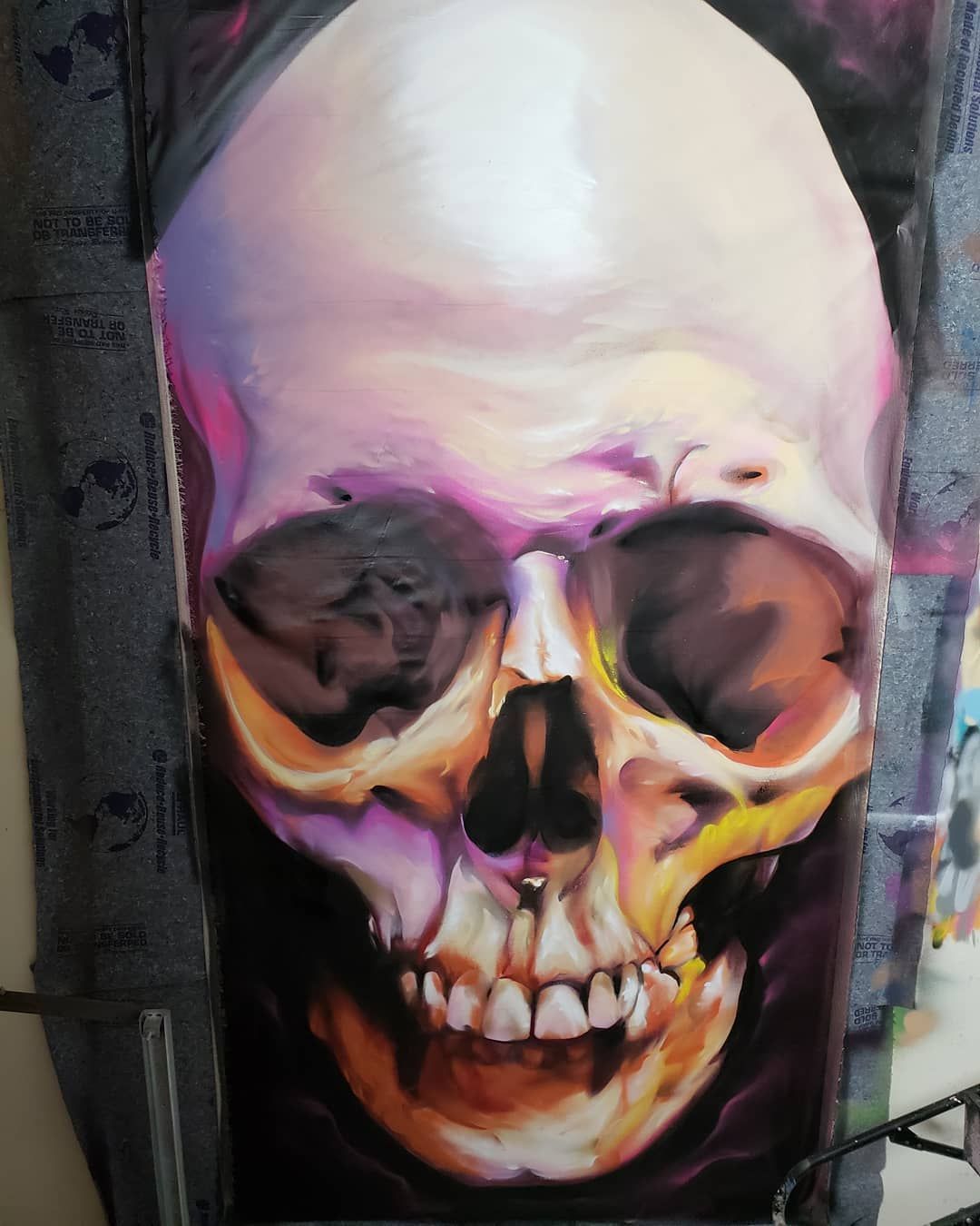 Human skull study painted freehand in aerosol with warm pink and orange tones on canvas