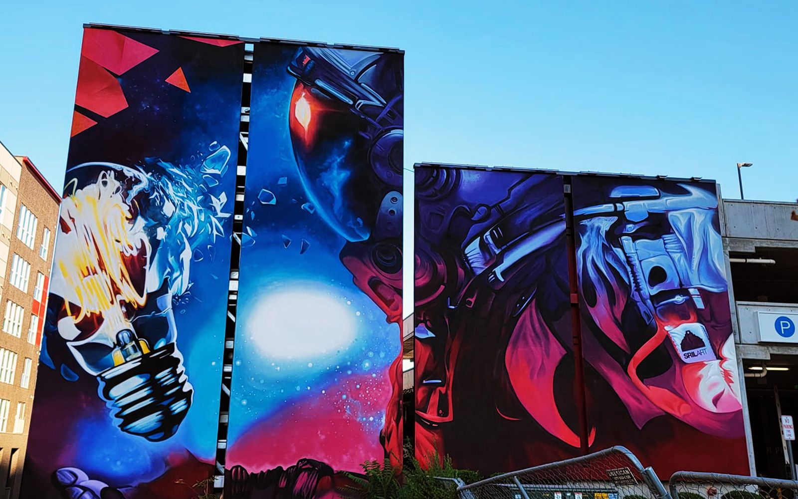 Astronaut gripping an exploding lightbulb, painted across two faces of a downtown Salt Lake City parking garage