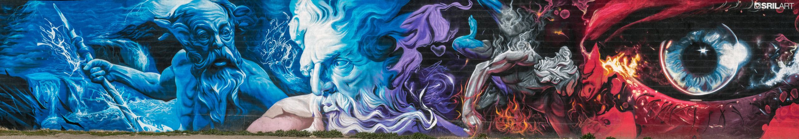 A long cinder-block wall painted end to end: bearded blue god, purple smoke, a falling figure in fire, and a giant eye