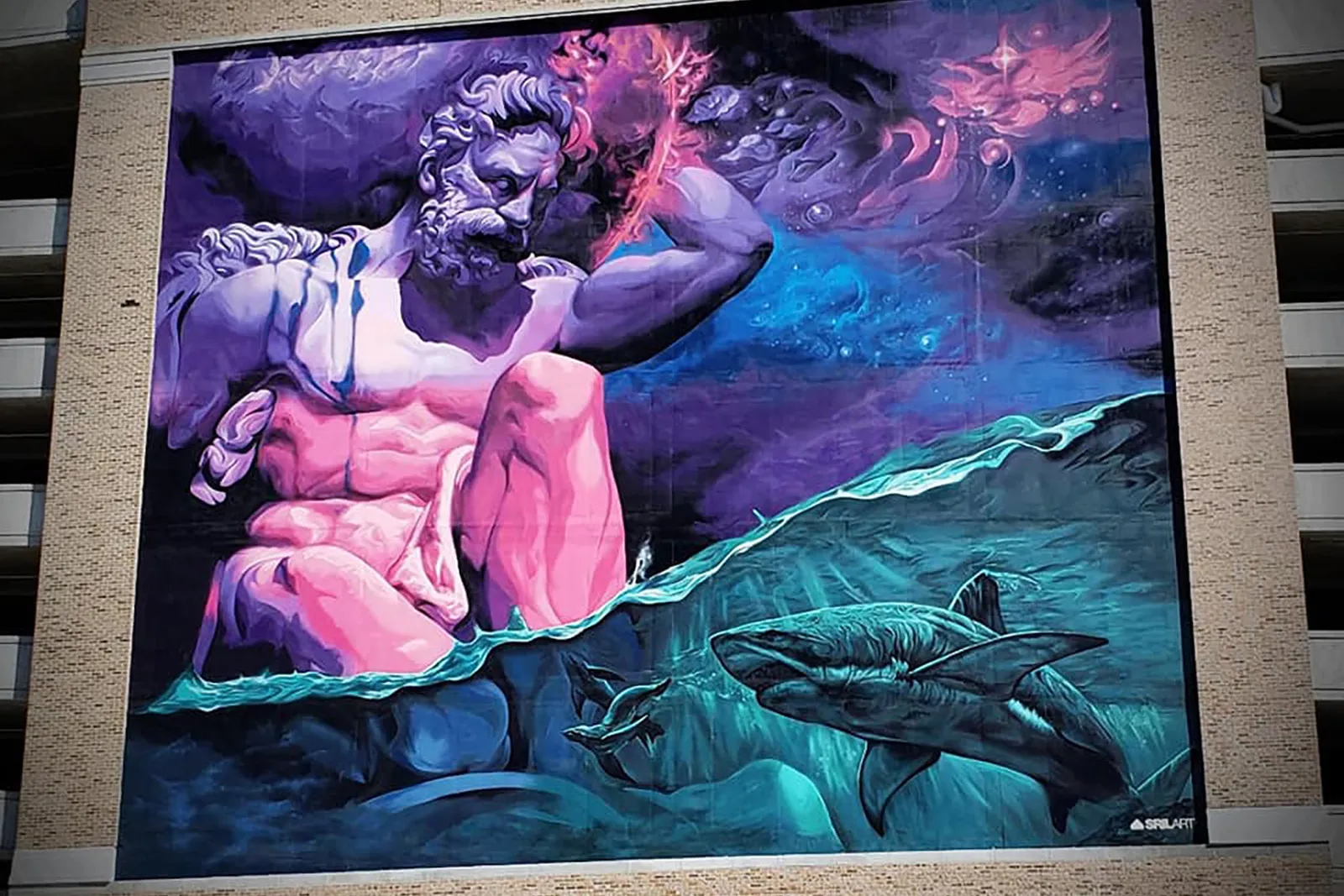 Bearded god in pink and purple reaching into a red nebula above a turquoise sea with sharks, painted across a building facade
