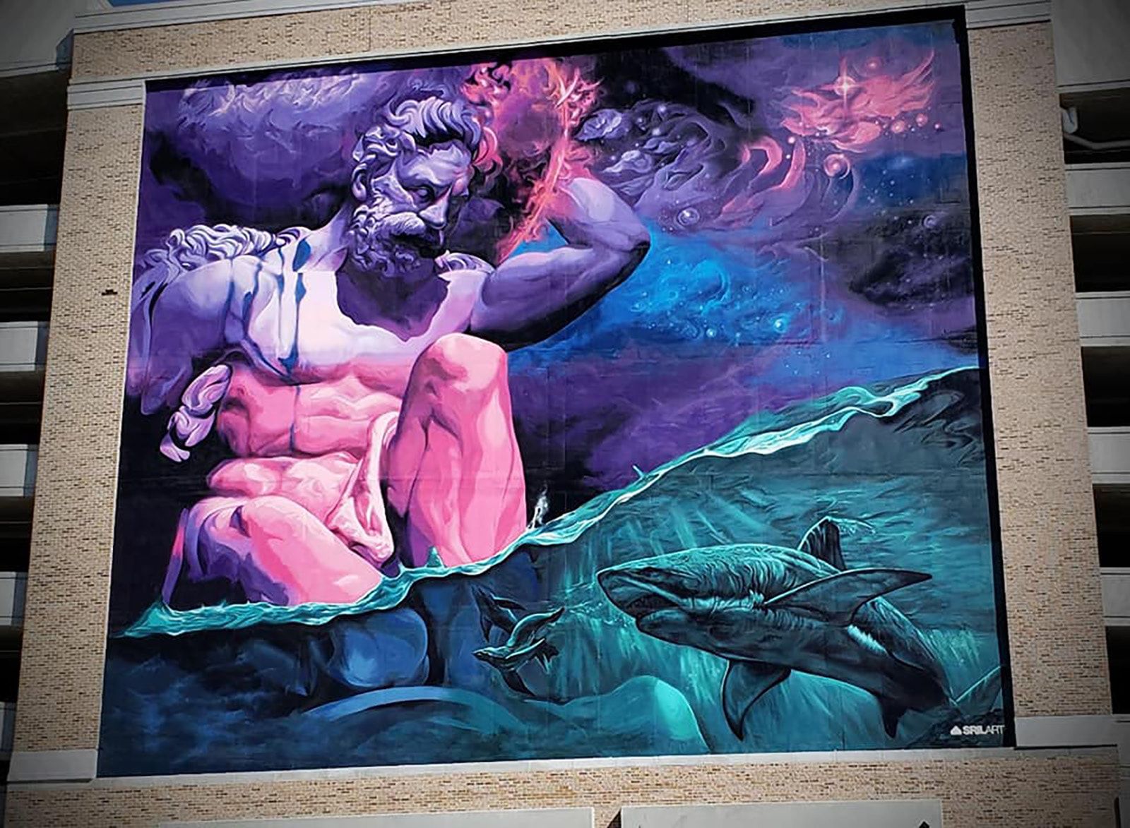 Bearded god in pink and purple reaching into a red nebula above a turquoise sea with sharks, painted across a building facade