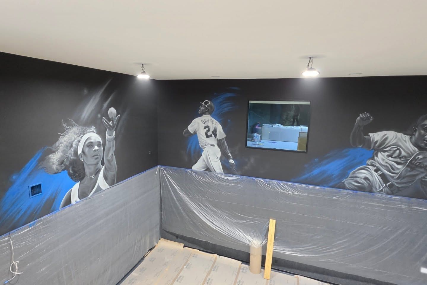 Grayscale athlete portraits painted across the charcoal walls of a private home court