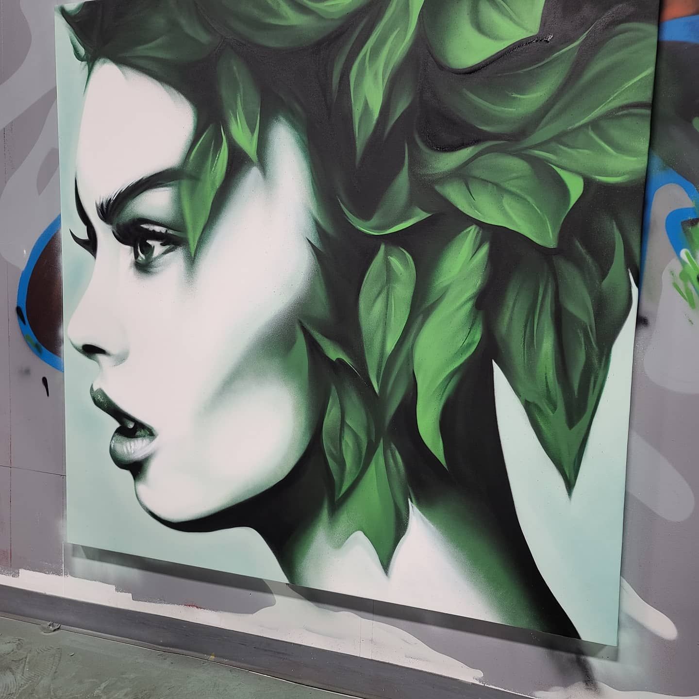 Aerosol canvas of a woman in profile, her hair rendered as dense green leaves