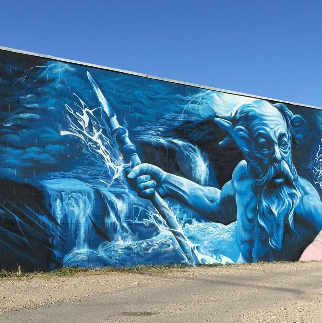 Neptune raising a trident out of breaking water, painted in blues across a cinder-block wall