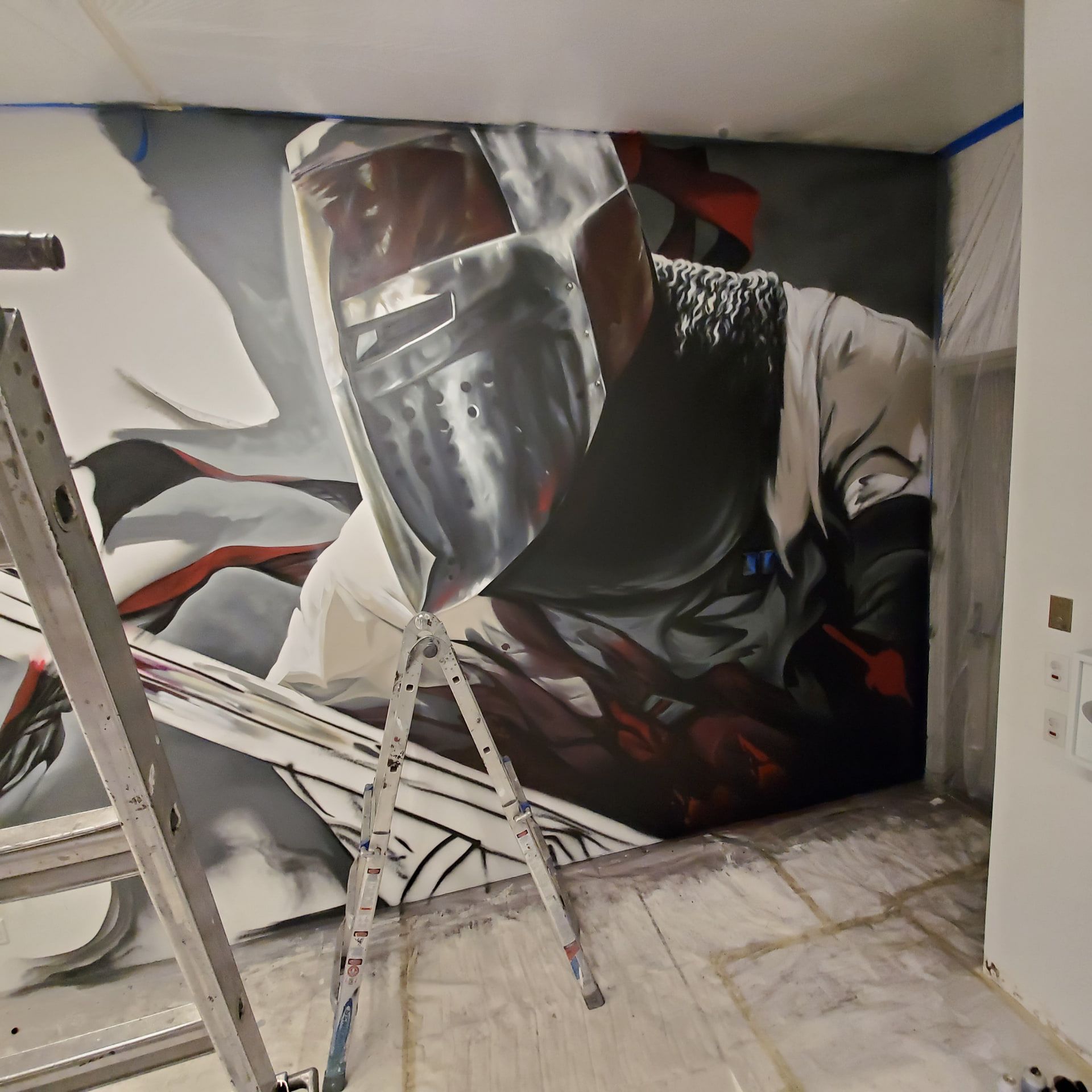 Visored helmet and sword emerging from gray smoke on the wall, a stepladder leaning below the unfinished lower half
