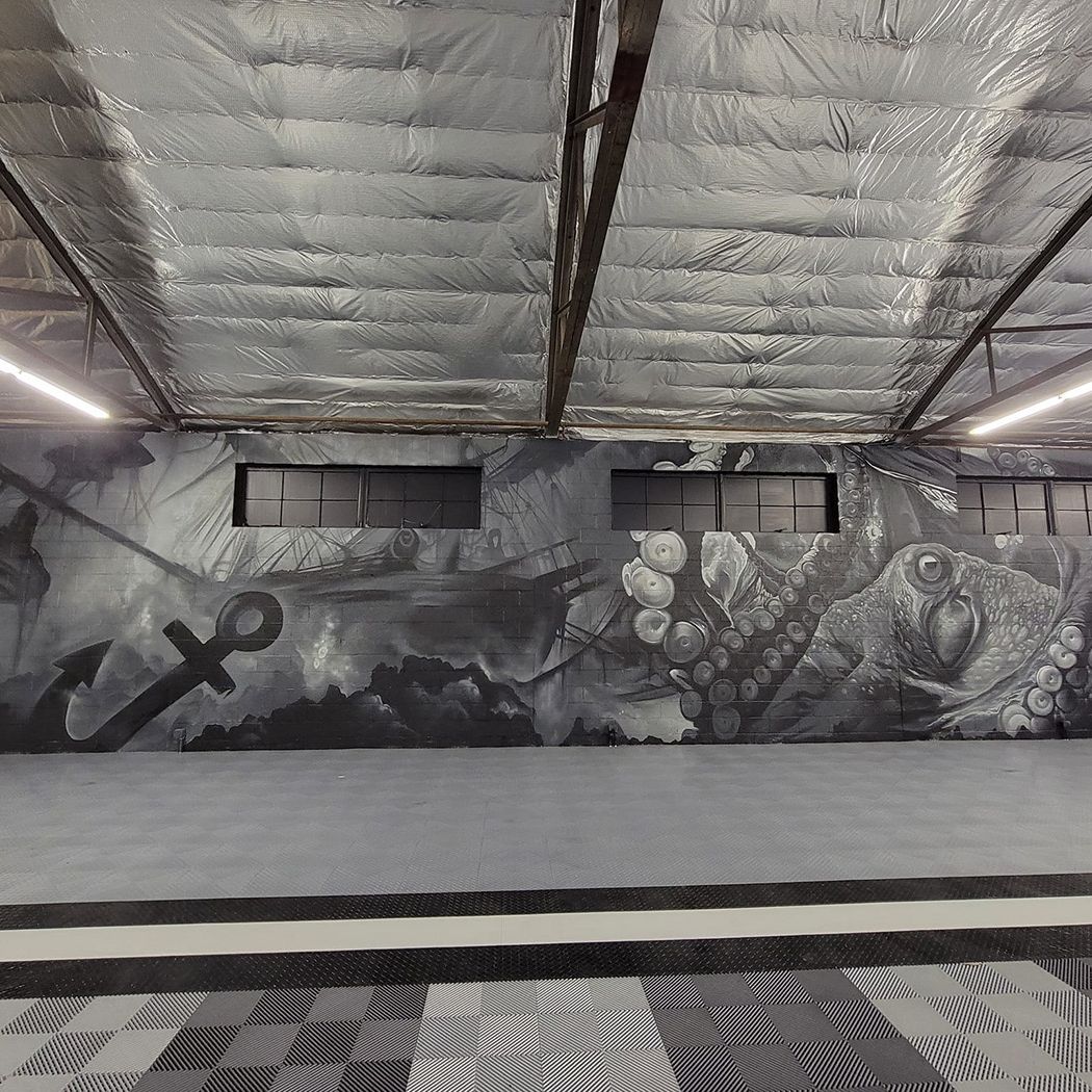 Black-and-white shipwreck and octopus mural spanning an indoor garage wall