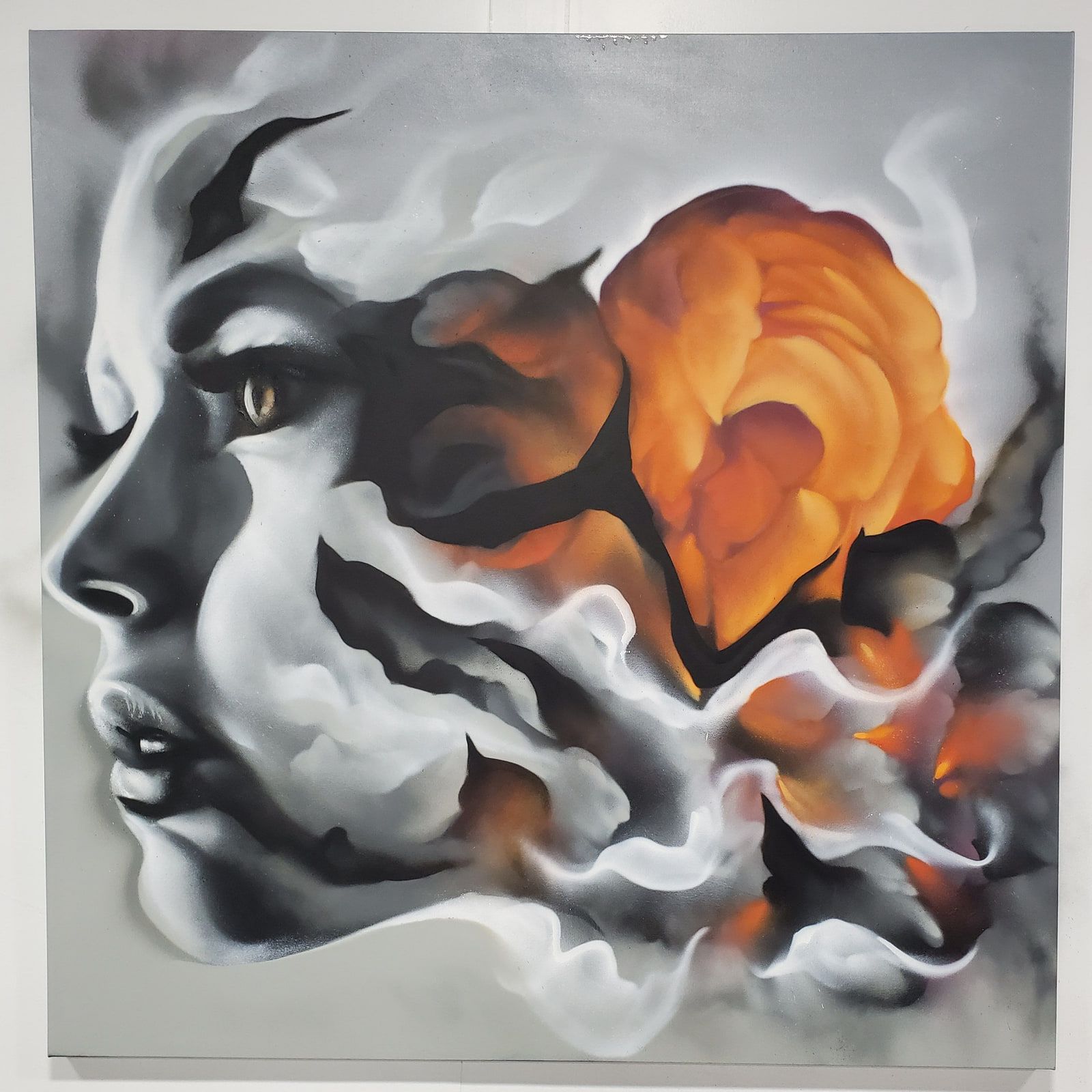 Face in profile dissolving into black and white smoke around a single orange rose, on a large square canvas
