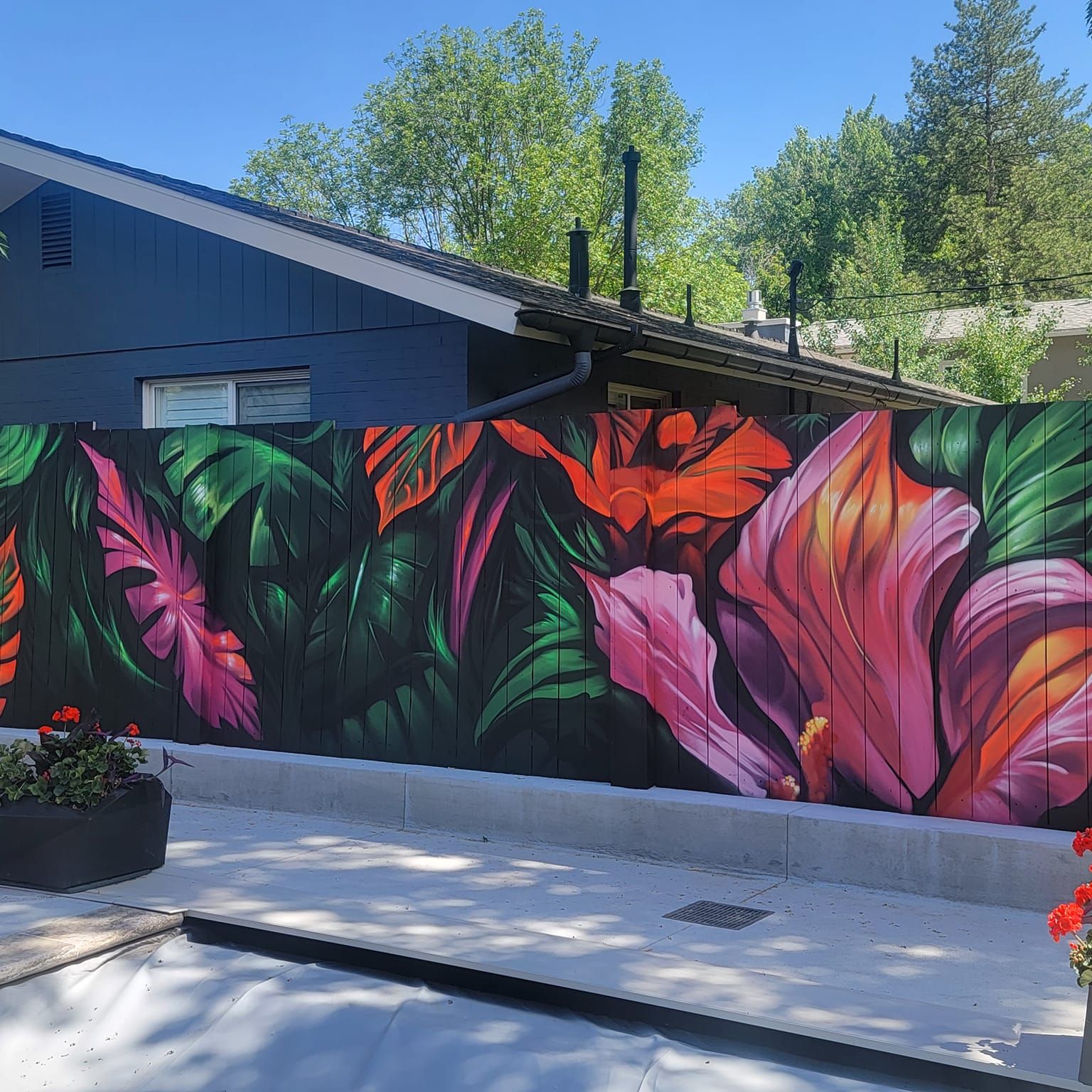 Vivid tropical flowers and leaves mural painted across a backyard wood fence